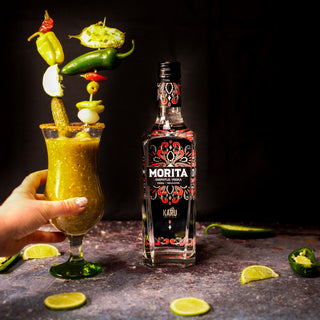 Hand picking up a Morita Chipotle Vodka Bloody Mary Cocktail garnished with sky high pickles and peppers