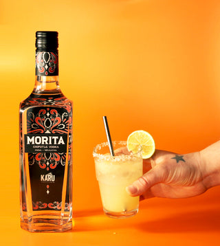Hand reaching out to pick up a margarita cocktail next to a bottle of Karu Distillery Morita Chipotle Vodka
