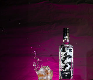 Bottle of Affinity Gin with a glass of ice on a purple background