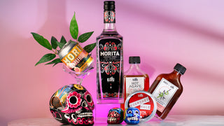 Bottle of Morita Chipotle Vodka by Karu Distillery and hot sauce with decorative handpainted skulls from Mexico and plant elements on a pink background